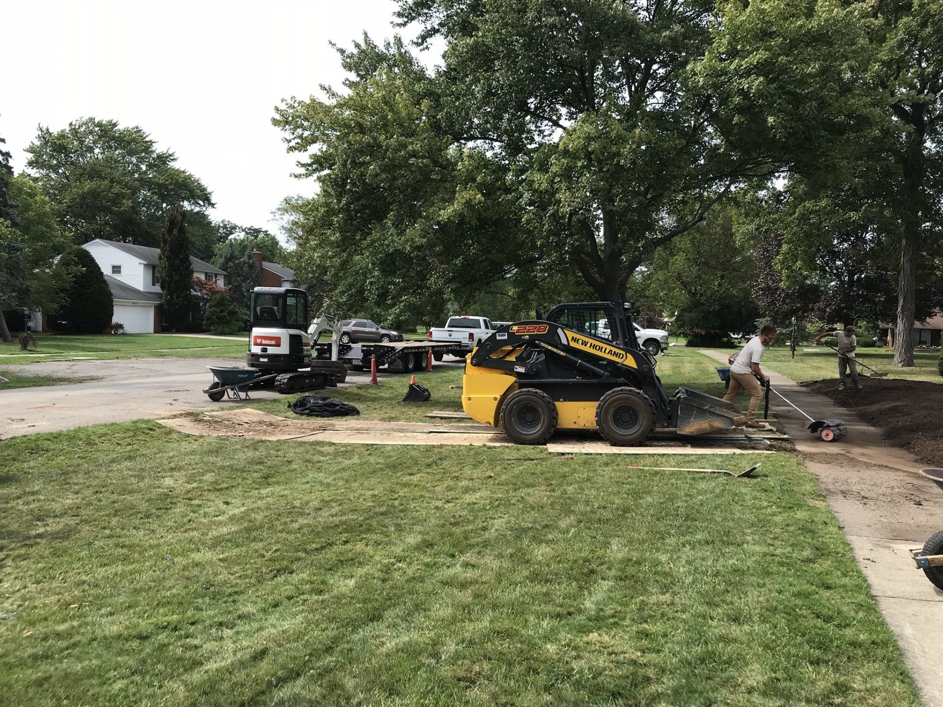 A yellow tractor is parked in a grassy yard next to a tree.