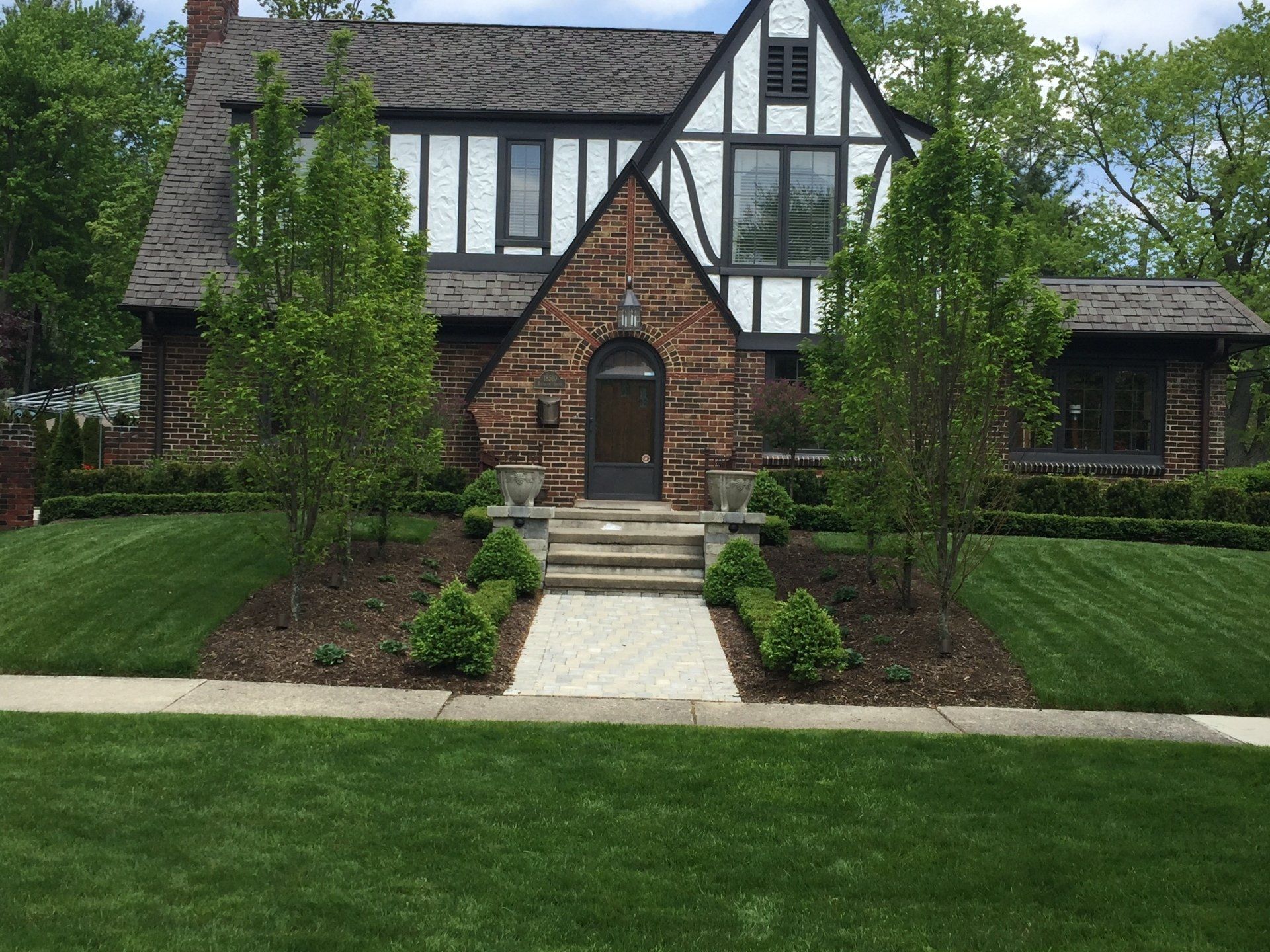 A large brick house with a lush green lawn in front of it.