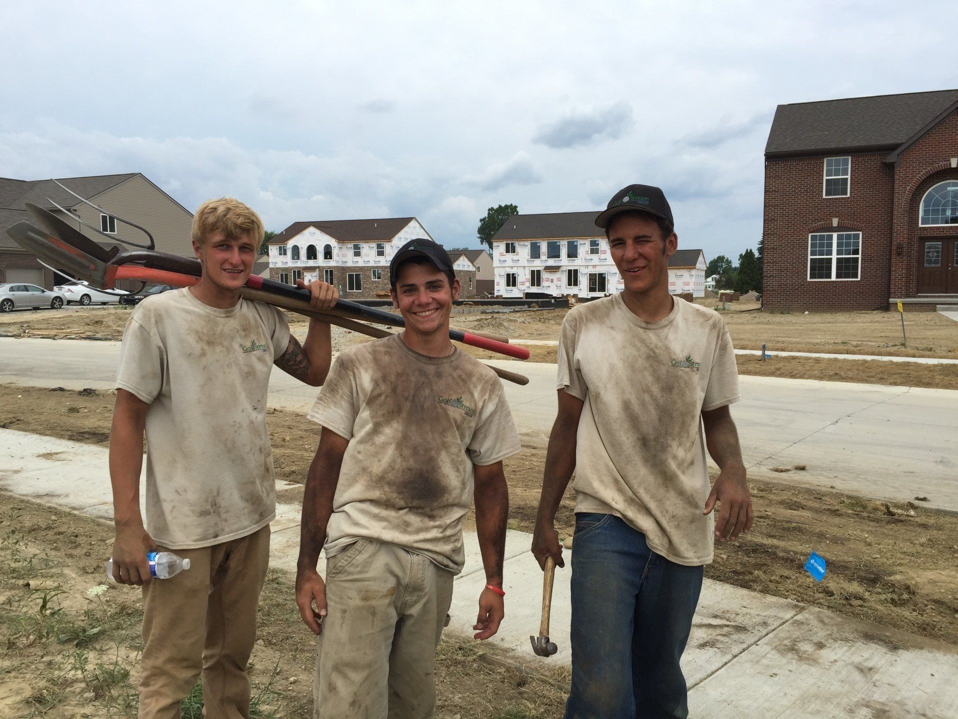 Three men are posing for a picture in front of a house