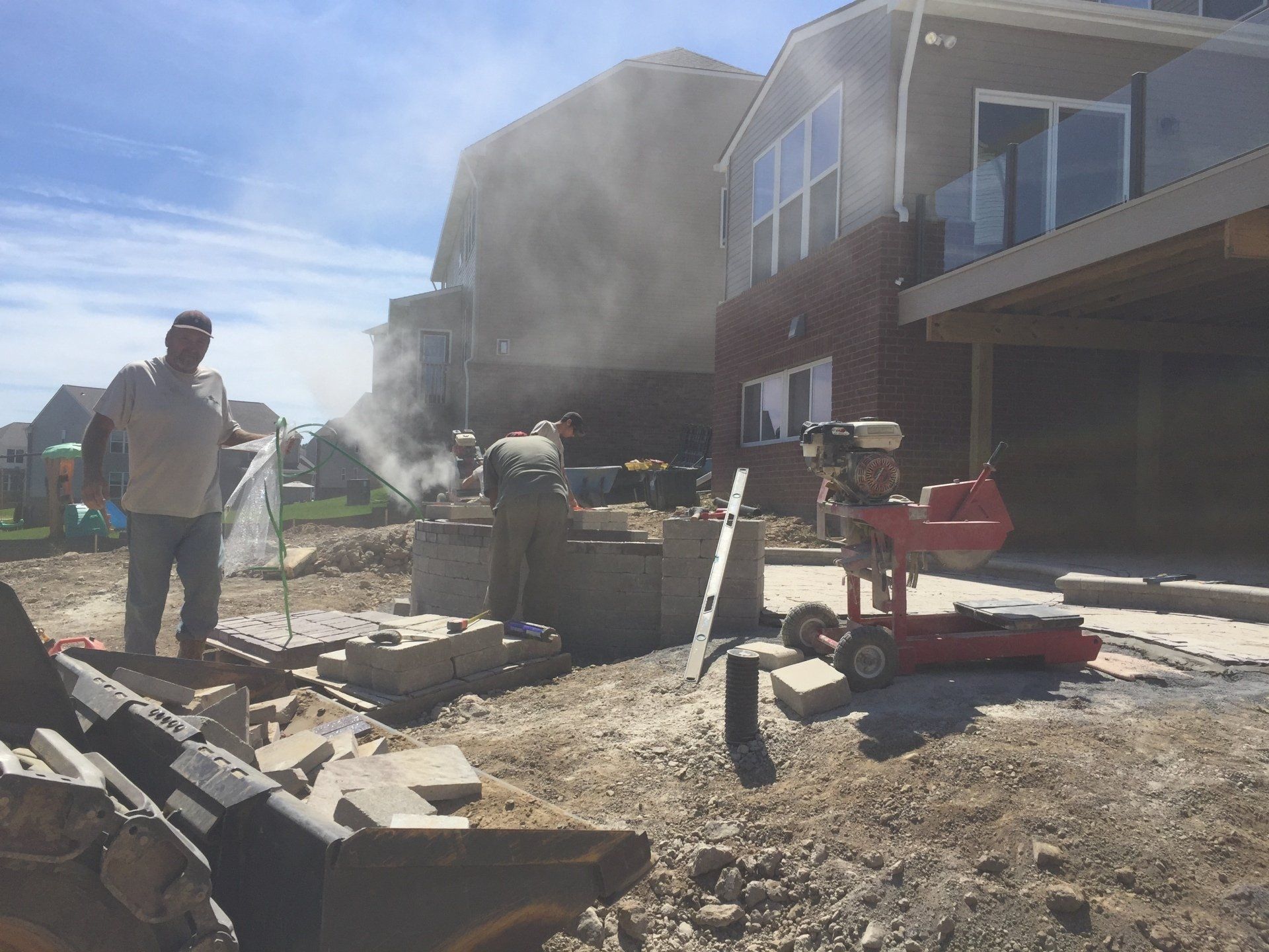 A man is standing in the dirt in front of a house.