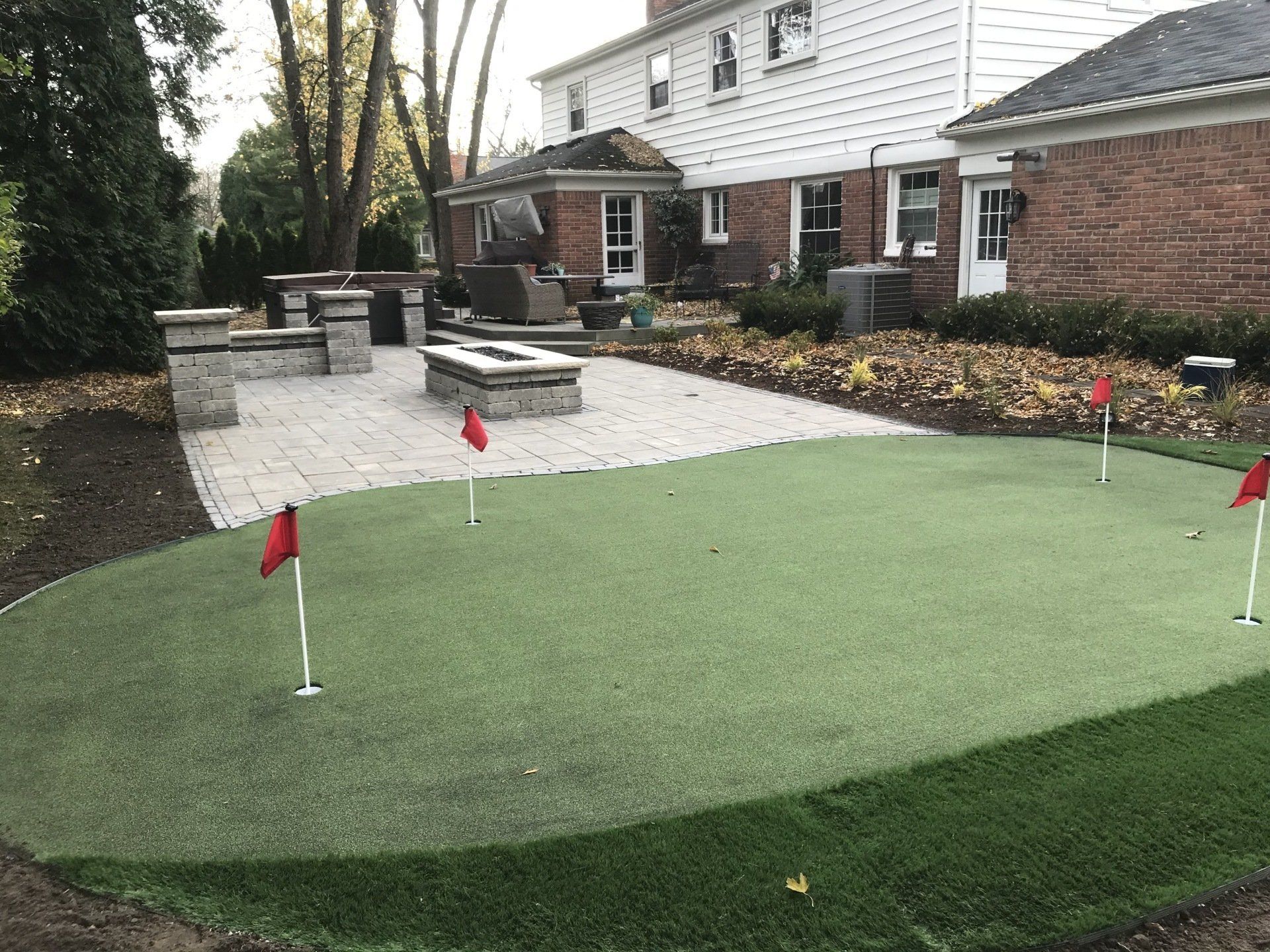 There is a putting green in the backyard of a house.