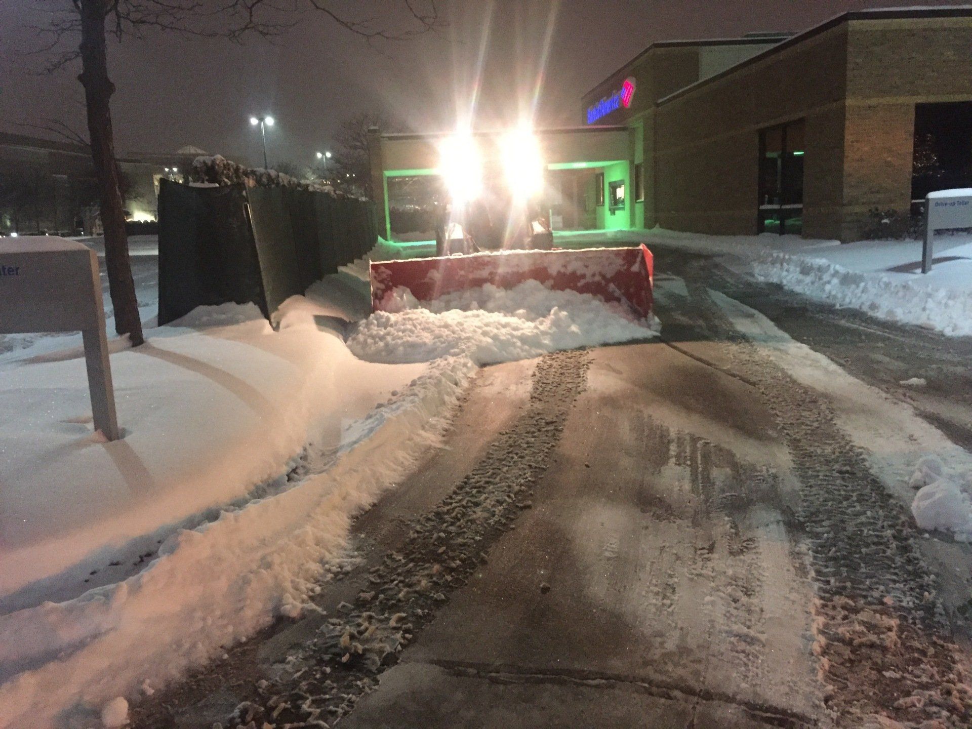 A snow plow is clearing snow from a street at night