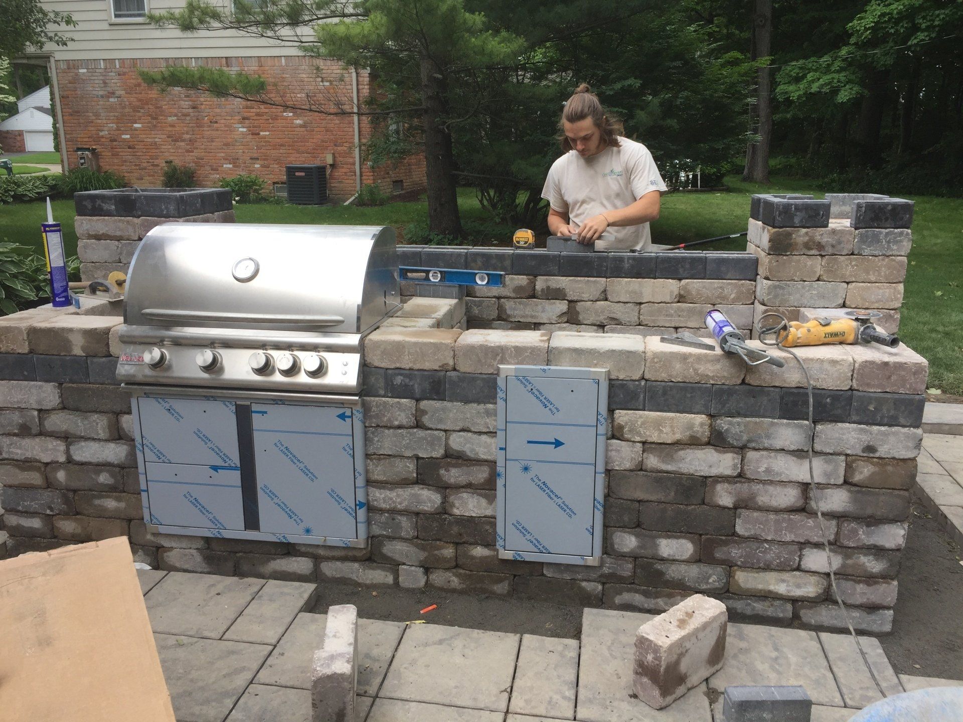 A man is working on a grill in a backyard