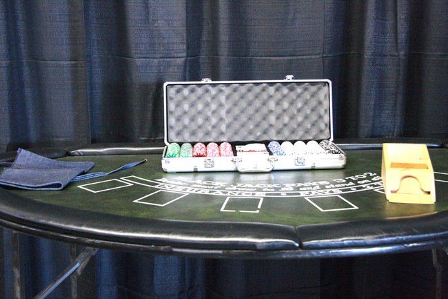 Poker chips and cards on a green felt table with a black case and yellow chip tray.