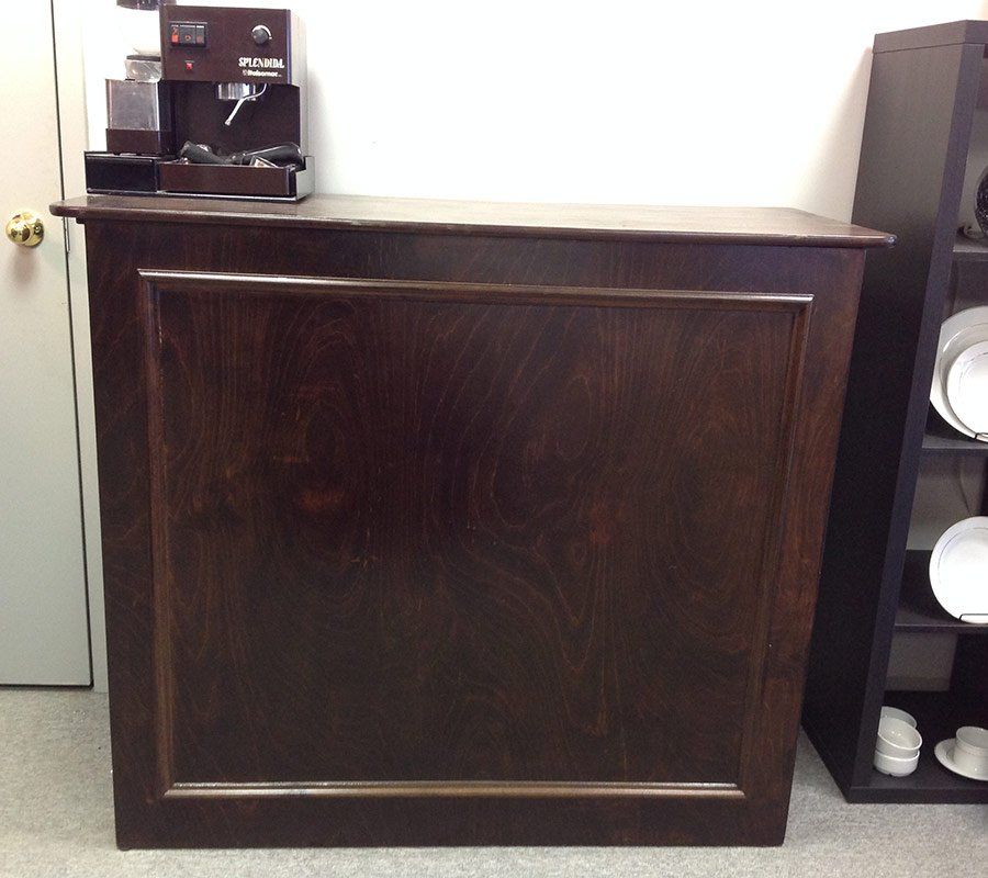 Dark wooden counter with a coffee machine on top in an office break room.