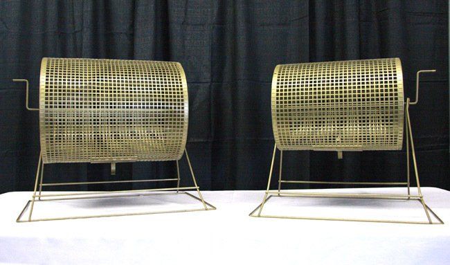 Two wicker raffle drums on metal stands against a black curtain backdrop