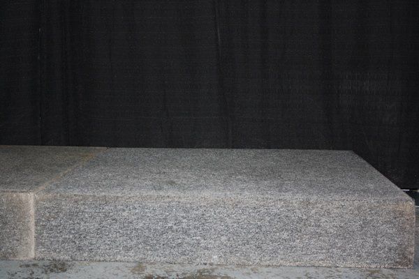 Gray stone steps against a dark wall, viewed from the front.