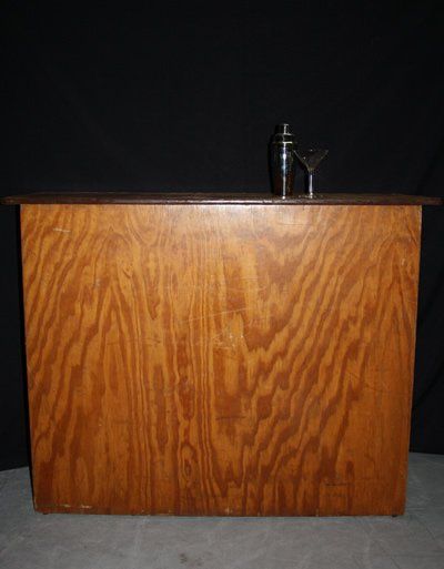 Wooden podium or cabinet against a dark background, with a small black fixture on top.
