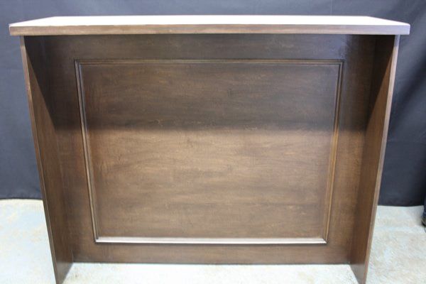 Dark wooden cabinet with a paneled front and light-colored top against a plain background