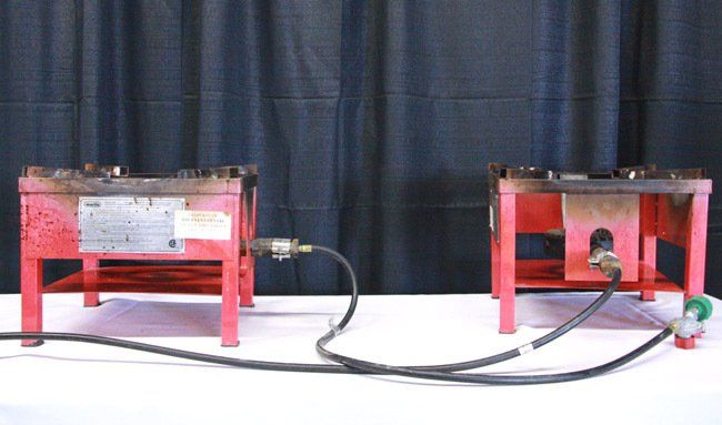 Two small red test rigs connected by black hoses on a white table against a dark backdrop