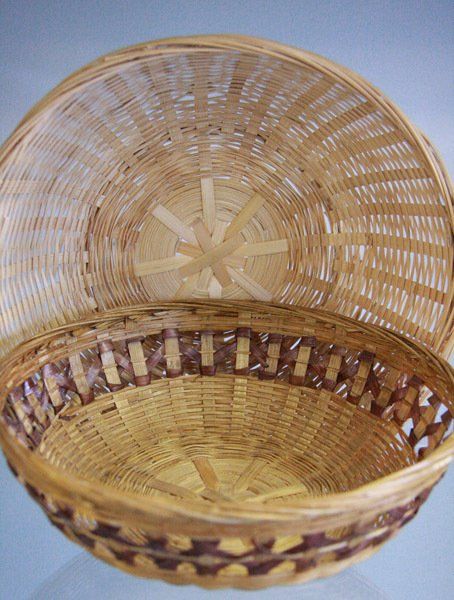 Empty woven basket with a rounded lid, made of light tan and brown wicker.