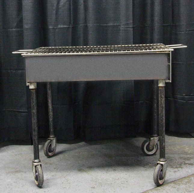 Stainless steel utility cart with wire top shelf and four casters against a black curtain backdrop