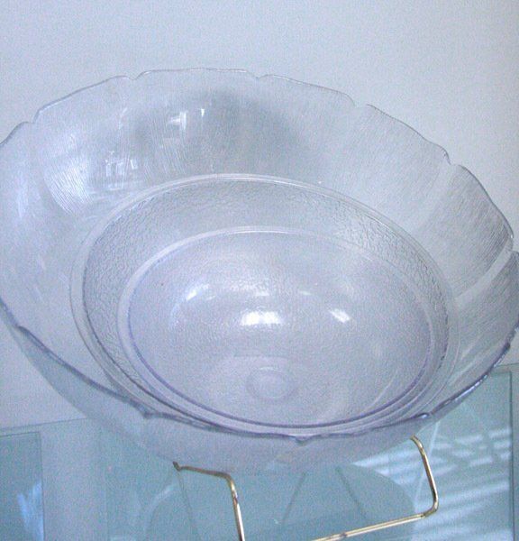 Transparent glass bowl on a metal stand against a light background