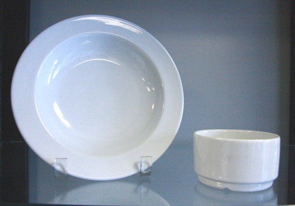 White dinner plate and small white bowl displayed on a reflective shelf.