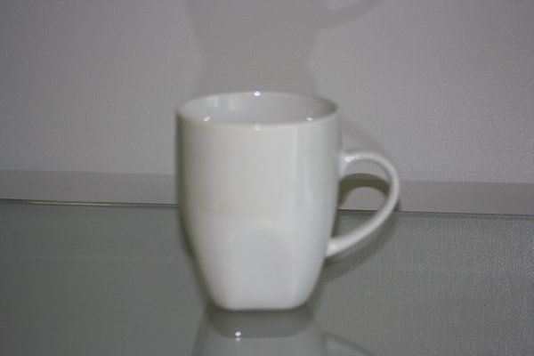White ceramic mug on a gray tabletop against a plain wall.