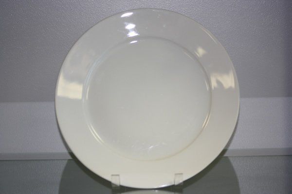 Plain white plate on a reflective surface against a gray background