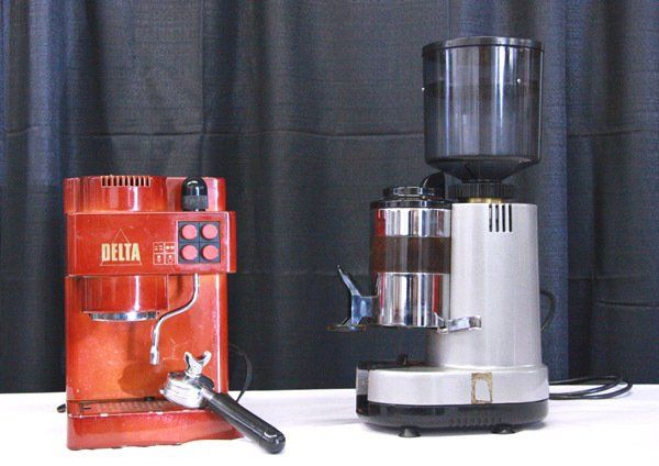 Two espresso machines on a black backdrop, one red and one silver, with a portafilter attached.