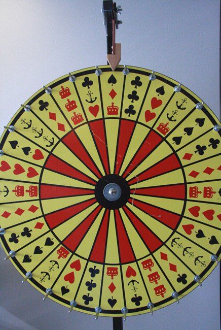 Colorful spinning wheel with card suit symbols, hanging outdoors against the sky