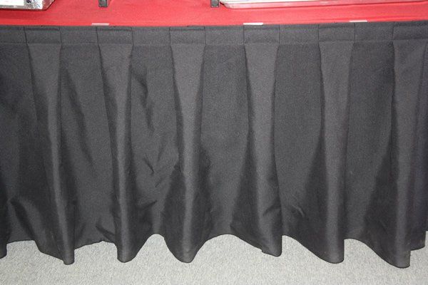 Black pleated table skirt beneath a red tabletop edge