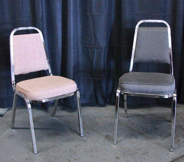 Two metal chairs, one with a beige seat and one with a gray seat, in front of a dark curtain.