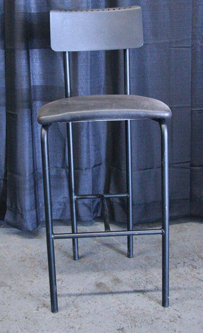 Tall gray bar stool with backrest and dark metal legs against a curtain backdrop