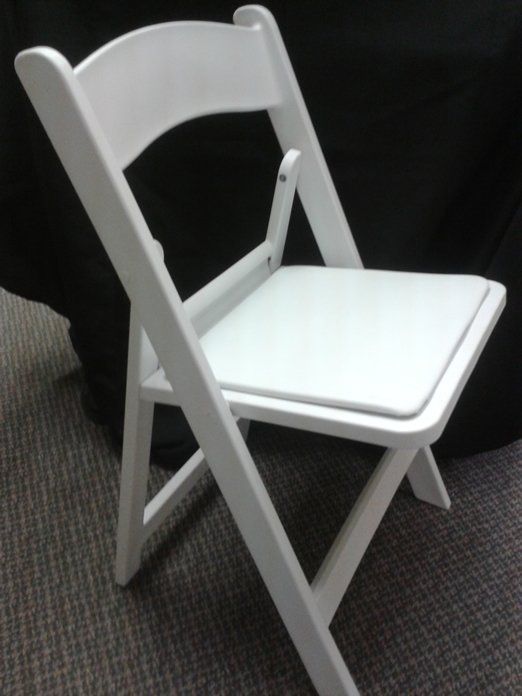 White folding chair on dark carpet against a black background