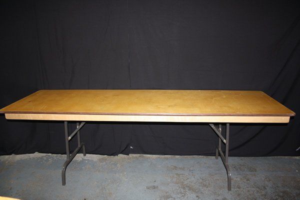 Folding banquet table with wood top and metal legs against a black backdrop