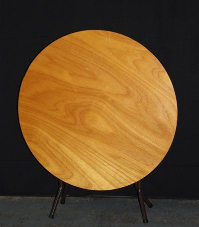 Round wooden tabletop on a dark metal stand against a black background