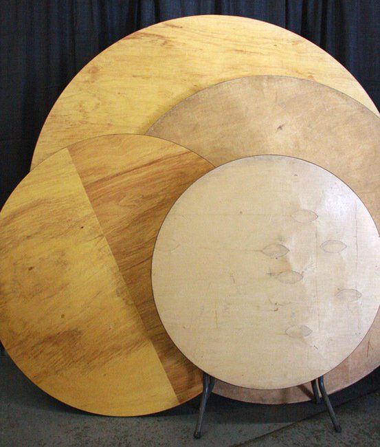 Three overlapping circular wooden boards in warm beige and tan tones on a dark background