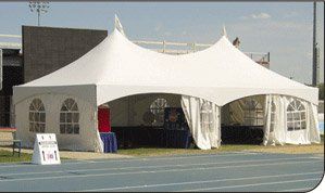 White event tent on a sports field with arched openings and banners at the entrance