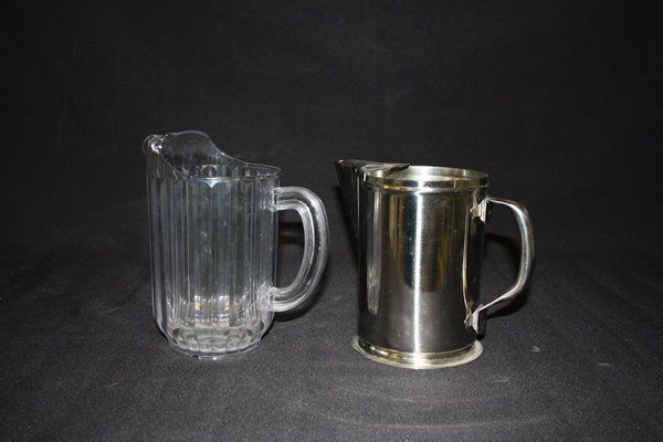 Two clear glass pitchers, one frosted metal pitcher, side by side on a dark background