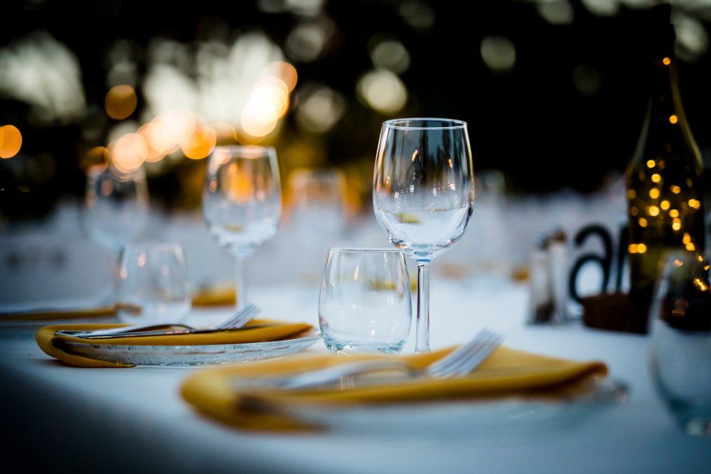 Elegantly set dining table with wine glasses, folded napkins, and warm candlelight bokeh