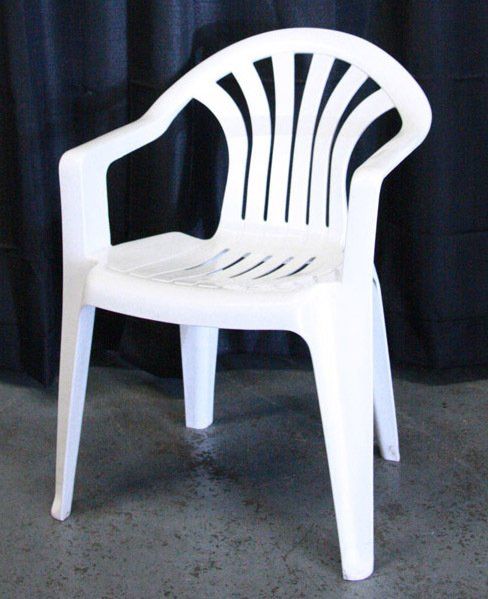 White plastic outdoor chair against a dark curtain backdrop