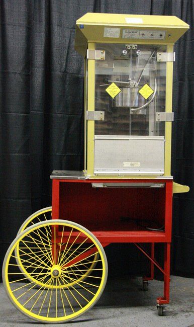 Yellow and red popcorn cart with glass display and a large yellow wheel, shown indoors.