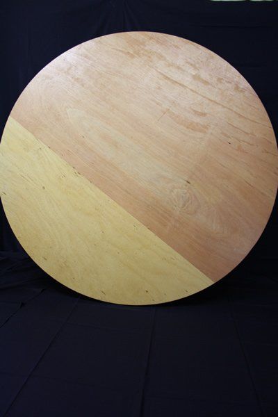 Round wooden tabletop with light wood grain on a dark background