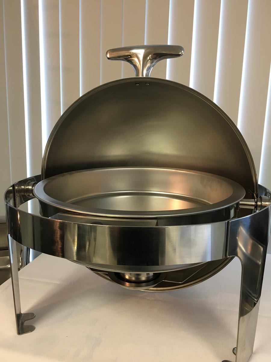 Stainless steel chafing dish with a dome lid on a stand against vertical blinds