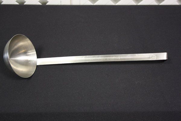 Stainless steel ladle with a long handle on a dark surface