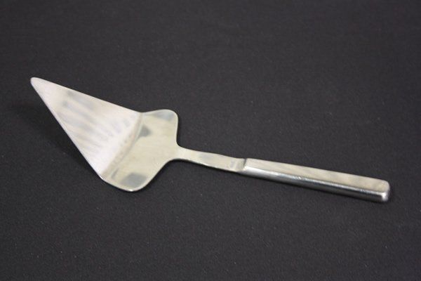 Metal cake server with a triangular blade on a dark background