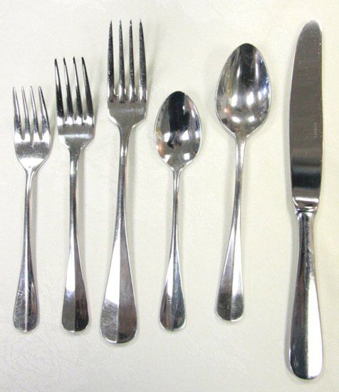 Assorted silverware—three forks, a teaspoon, tablespoon, and knife—lined up on a white background