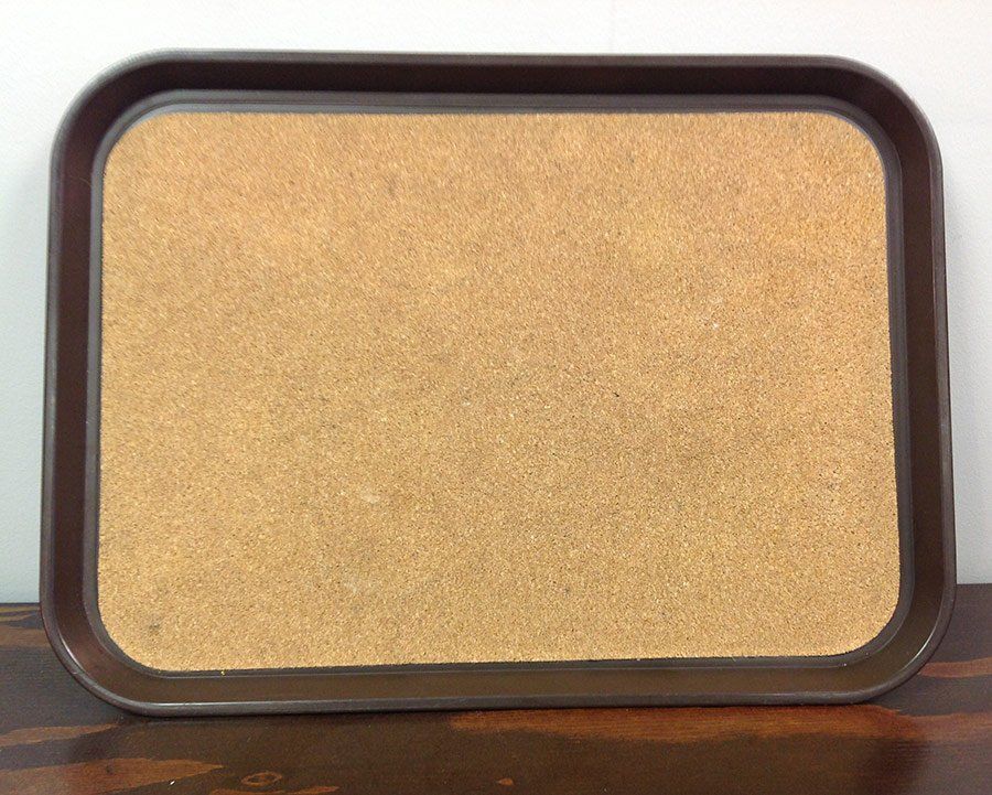 Empty rectangular corkboard with a dark brown frame on a wooden surface.