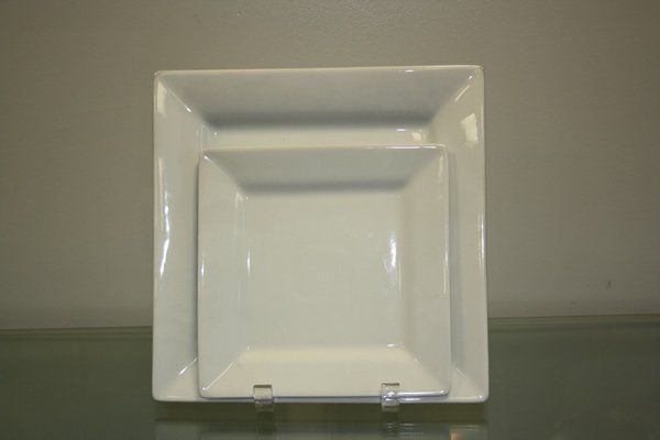 White square plate with a raised rim on a gray surface.