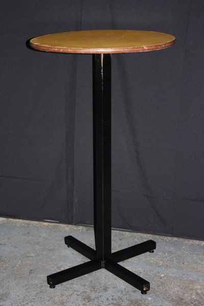 Round wooden tabletop on a black pedestal base against a dark backdrop.