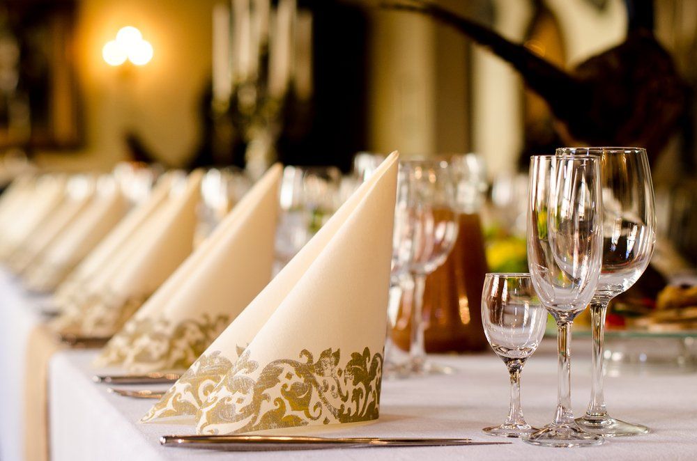 Elegant banquet table with folded cream napkins and wine glasses set in rows