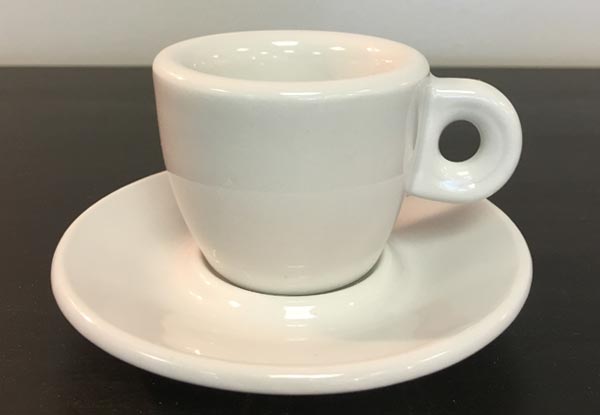 White espresso cup on a matching saucer against a dark background