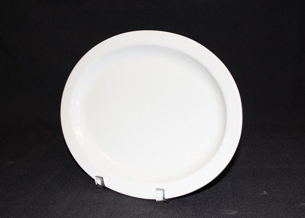 White round plate on a black background, displayed on a small stand.