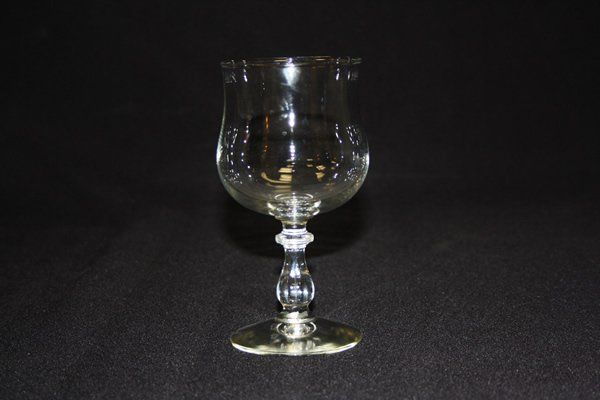 Clear glass goblet on a dark background, centered and illuminated by flash