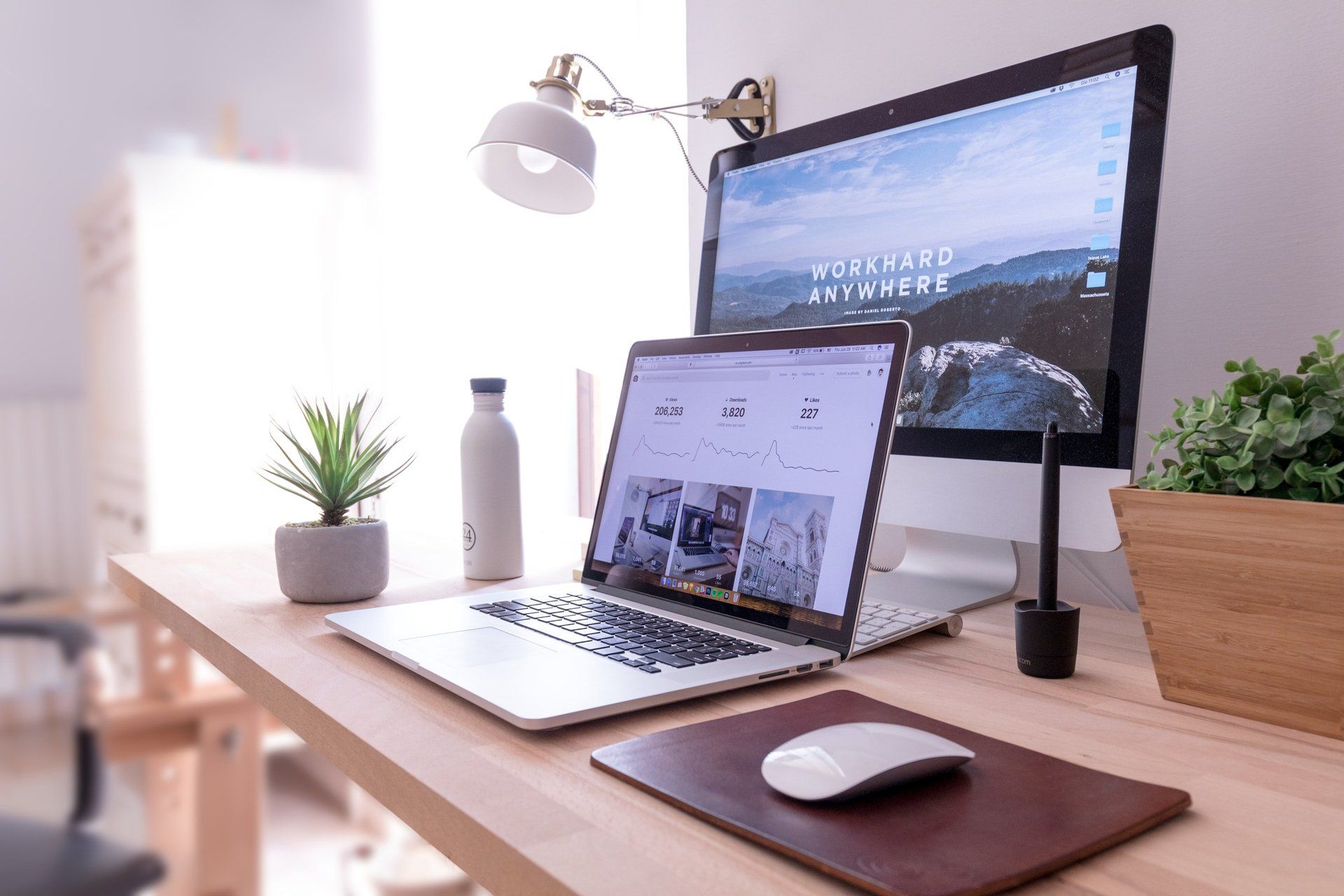 apple laptop on desk in front of mac desktop computer