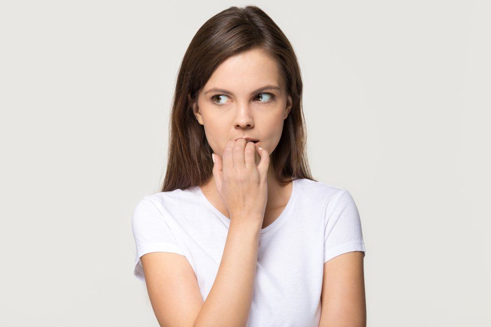 Nervous insecure young woman looking aside feeling fear uncertainty worried scared biting nails, str