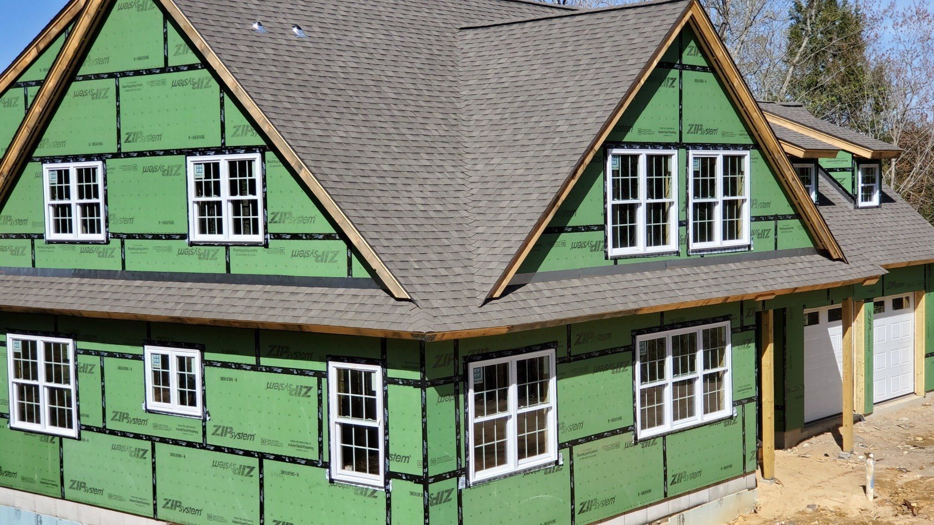 A house is being built with green zipsystem panels and a gray roof.
