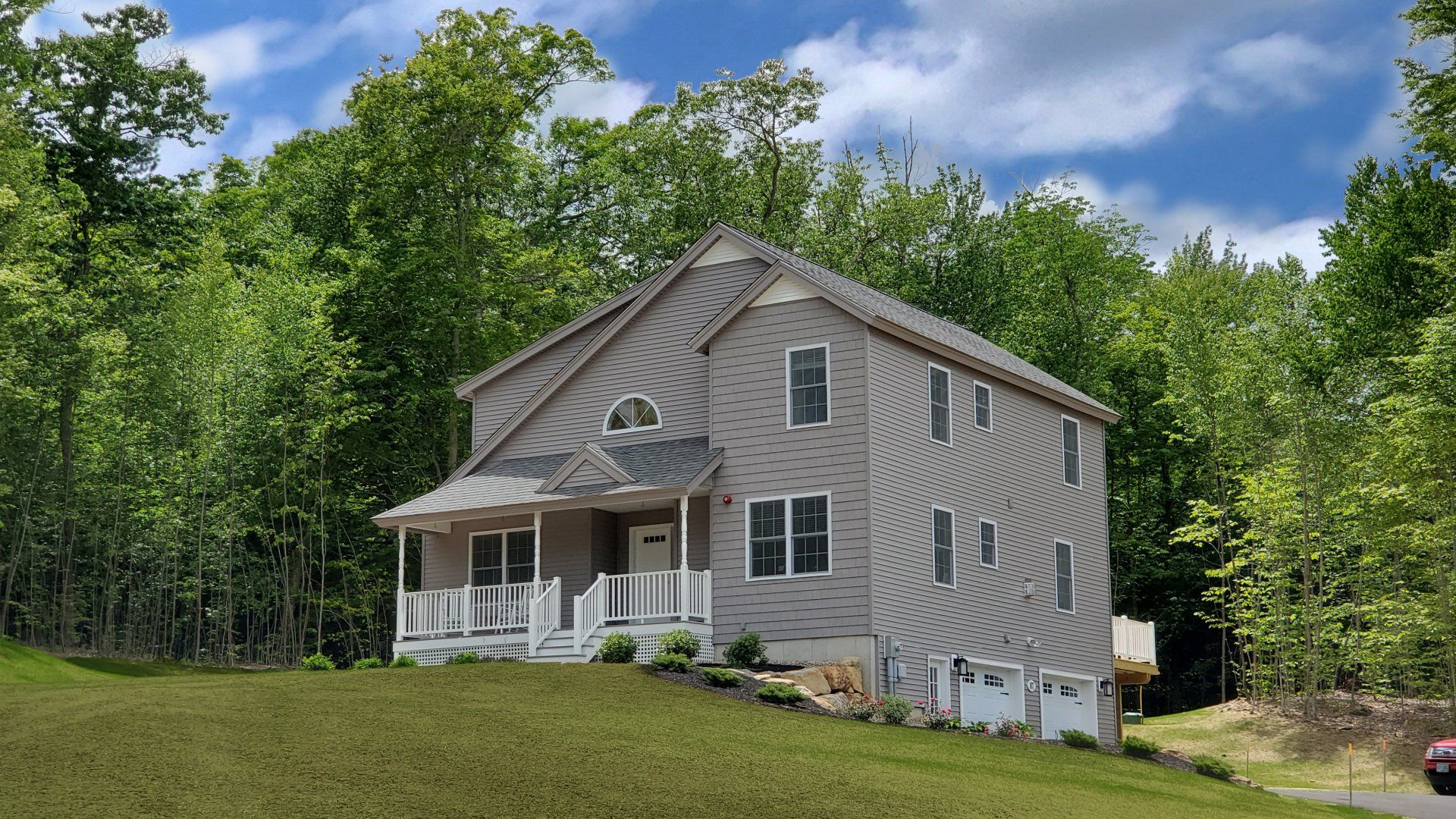 A house is sitting on top of a grassy hill surrounded by trees.